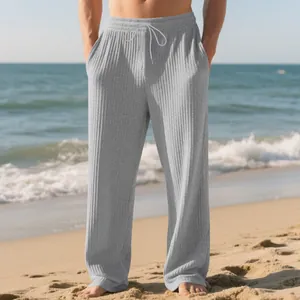 Detail view of grey ribbed wide-leg trousers with drawstring on a sunny beach