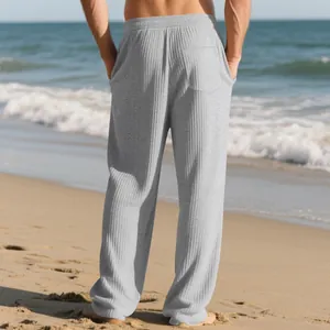 Detailed back view of men's grey ribbed casual pants worn on a sunny beach setting