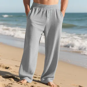 Detailed view of men's gray ribbed wide-leg trousers with drawstring at the beach