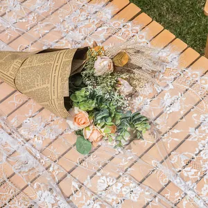 Gedetailleerd overzicht van puur wit gebloemd kanten tafelkleed met wimperrand