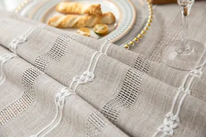 Close-up of rustic cotton linen tablecloth with white embroidery and openwork detail