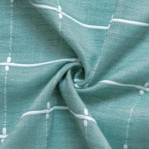 Detailansicht einer mintgrünen Tischdecke mit feiner Stofftextur und Stickmuster