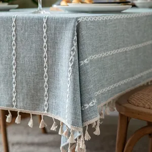 Detailed view of light blue linen-like tablecloth with white stitching and tassels