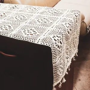 Detailed view of a vintage white lace crochet table runner featuring elegant hollow floral patterns