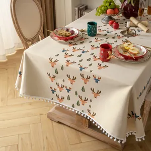 Tovaglia natalizia jacquard con renne e bordo a pompon bianchi su tavolo da pranzo