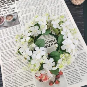 Close-up of artificial white wild flower wreath on a vintage newspaper background.