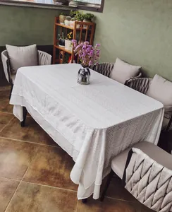 Detail view of white embroidered lace tablecloth on an outdoor dining table setup.