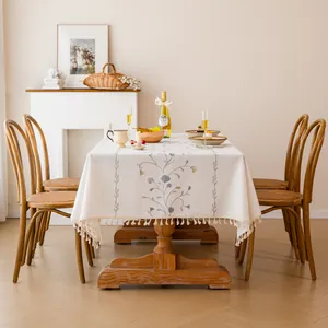 Detailed lifestyle shot of an embroidered floral tablecloth with elegant tassel fringe