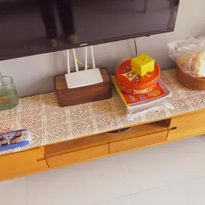 A detailed view of a vintage hollow lace crochet table runner on a wooden TV cabinet.