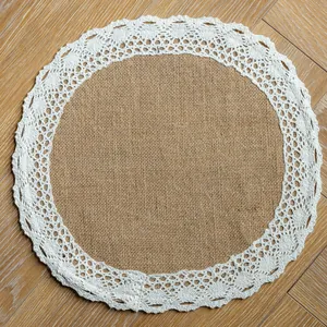 Detailed overhead view of a round burlap placemat with white lace border on wooden floor
