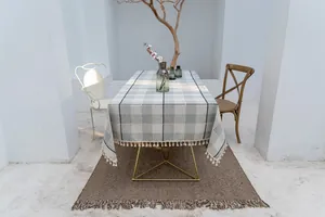 Elegante grau-weiße Tischdecke aus Baumwollleinen mit Fransen in minimalistischer Umgebung