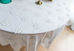 Vue détaillée d'élégantes broderies florales blanches sur une nappe en dentelle vintage