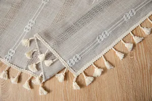 Detail of vintage linen tablecloth featuring white floral embroidery and tassels
