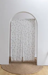 Minimalist floral cotton door curtain with tassel trim hanging in an arched doorway
