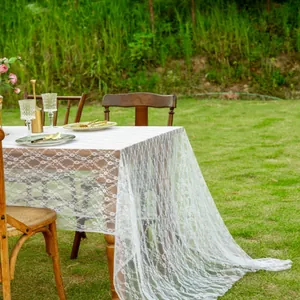 Vue détaillée d'une nappe en dentelle blanche avec motifs floraux dans un jardin.
