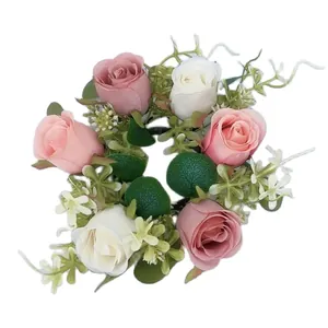 Detail view of a floral candle ring with artificial pink and white roses and eucalyptus leaves.