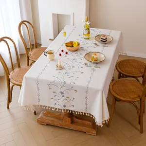 Elegant embroidered floral tablecloth with fringe tassels shown in a cozy dining room setting