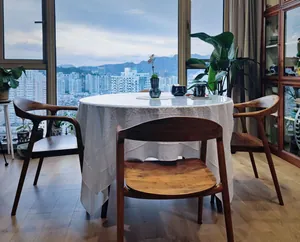 Elegant French white embroidered lace tablecloth on a round table in a high-rise home setting.
