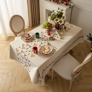Elegante tovaglia natalizia in jacquard con renne e nappe a pompon su una tavola apparecchiata.