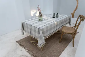 Detail der grau-weiß karierten Tischdecke aus Baumwollleinen mit dekorativen Quastenfransen