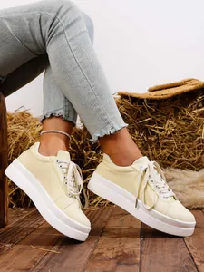 Detail view of light yellow thick sole casual sneakers with white platform and laces