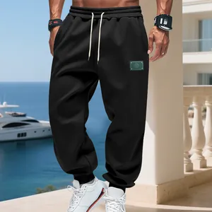 Detail view of men's black loose fleece joggers with elastic cuffs and drawstring waist.