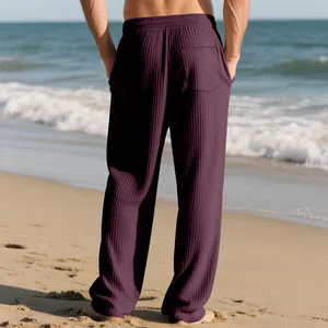 Back view of men's loose purple jacquard striped casual pants worn on a sandy beach