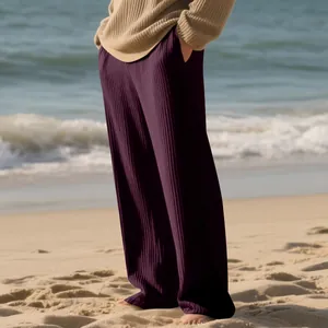 Macro detail of men's plum ribbed wide-leg pants on a beach showing rich fabric texture
