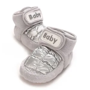 Detaillierte Nahaufnahme warmer grauer Baby-Winterschuhe mit silberner Steppung und Klettband