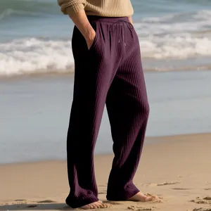 Close-up view of men's purple ribbed wide-leg trousers with adjustable drawstring at the beach