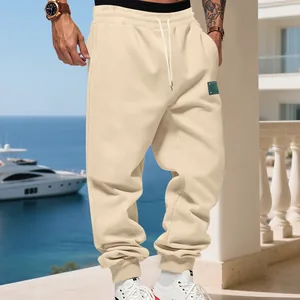 Detail of men's cream fleece-lined joggers with drawstring waist and tapered cuffs in resort setting.