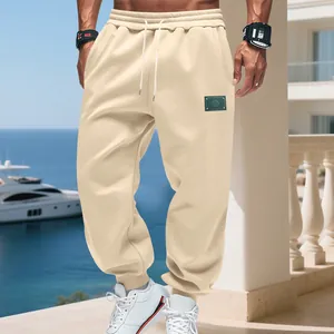 Detail of beige fleece joggers featuring a drawstring waist and logo patch.