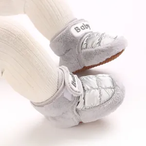 Nahaufnahme silberner gesteppter Baby-Winterschuhe mit grauem Kunstfell und Klettverschluss.
