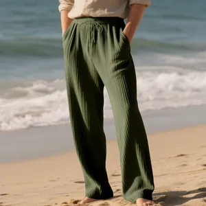 Detail of olive green pleated wide-leg men's pants with drawstring waist on beach