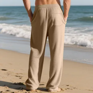 Rear view of men's loose fit ribbed striped wide-leg pants in khaki on a beach