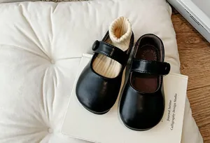 Detailed top-down view of classic black girls' Mary Jane flats on a white decorative book.