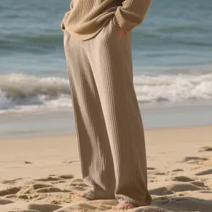 Detailed view of men's loose khaki ribbed wide-leg pants worn at a sunny beach setting