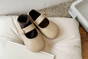 Detail view of beige girls Mary Jane shoes on a white cushion for spring style.