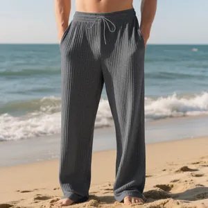 Detail view of men's grey ribbed striped wide-leg casual drawstring pants on a sunny beach