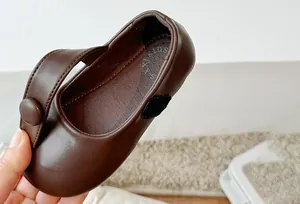 Detailed macro view of a brown leather girl's Mary Jane shoe with a secure velcro strap.