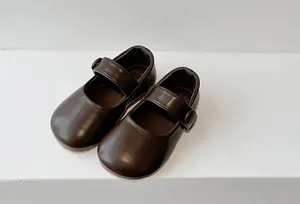 Close-up detail of dark brown girls' Mary Jane leather shoes with button strap