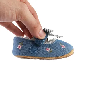 Close-up detail of a blue baby girl princess walking shoe with pink floral embroidery