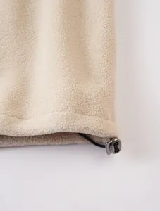 Primer plano detallado del dobladillo de una sudadera de forro polar beige con cordón ajustable