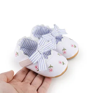 Close-up detail of newborn baby girl princess walker shoes with floral embroidery