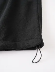 Primer plano del cordón ajustable en el dobladillo de una chaqueta de forro polar negro.