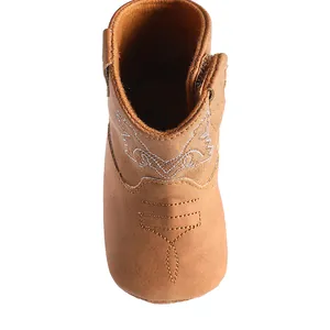Gros plan d'une botte western pour bébé marron avec broderie blanche et semelle souple