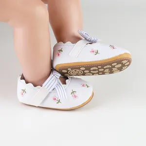 Detailed view of white baby princess shoes featuring pink floral embroidery and striped bows