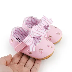 Close-up of pink infant Mary Jane shoes with floral embroidery and striped bow detail