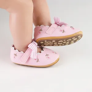 Close-up detail of pink baby girl walker shoes with floral embroidery and a striped bow
