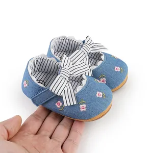 Macro view of blue denim baby girl princess shoes with floral embroidery and bow